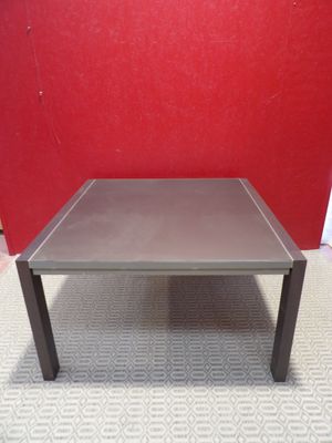 table basse grise posée sur un sol recouvert de moquette, devant un mur rouge