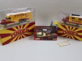 trois camions de pompiers miniatures dans leurs boîtes, posés sur une surface blanche