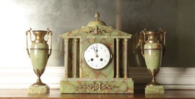 three vases and a clock sitting on a table