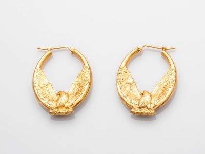 une image représentant une paire de boucles d'oreilles créoles en or sur fond blanc