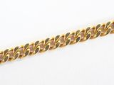 gros plan d'un bracelet en chaîne en or sur une surface blanche