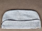 un gros plan d'un petit sac gris posé sur une surface marron