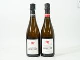 deux bouteilles de vin posées l'une à côté de l'autre sur une surface blanche