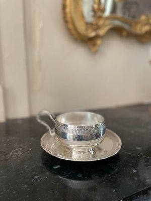 une tasse et une soucoupe argentées posées sur une table noire