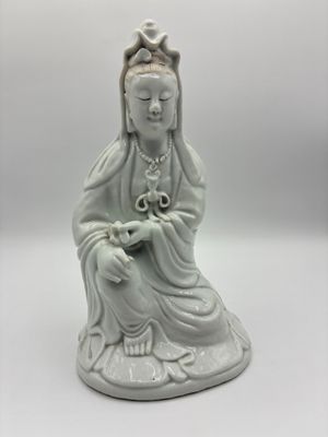 une statue blanche représentant une femme assise sur une table