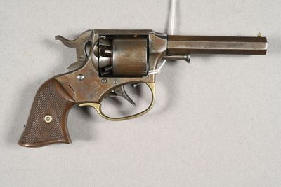 un gros plan d'un revolver posé sur une table, sur fond blanc