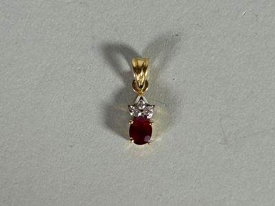 a close up of a red and white diamond pendant on a white surface