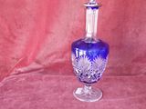 un vase en verre bleu avec un couvercle transparent, posé sur un tissu rouge