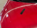 a close up of a red car with a sticker on it ' s hood