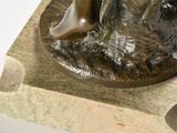 a bronze statue of a man sitting on a rock