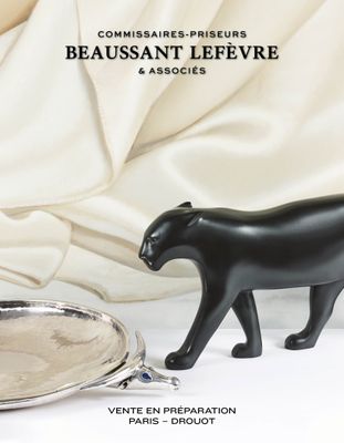 une figurine de chat noir posée à côté d'un plateau en argent