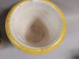 a yellow and white bowl sitting on a table next to an orange