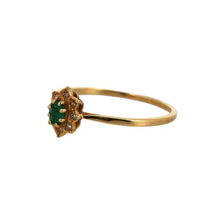 gros plan d'une bague en or avec une pierre verte