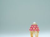 une bague en or ornée de pierres roses et de perles sur un fond blanc