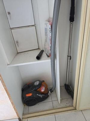 un aspirateur dans un coin de la salle de bains, la porte ouverte