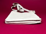 a white purse sitting on top of a pink surface