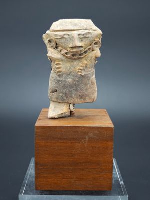 une petite statue en pierre représentant une femme, posée sur un socle en bois