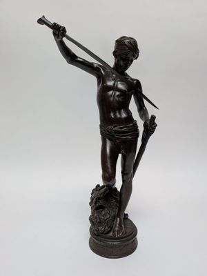 an antique bronze statue of a man holding a sword and a shield