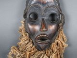 un gros plan sur un masque en bois aux longs cheveux