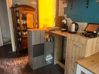 une petite cuisine avec une armoire en bois et un ordinateur portable posé sur le plan de travail