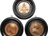three bronze medallions of a man and a woman on a white background