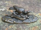 une statue en bronze représentant un oiseau posé sur une feuille