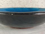 blue and black bowl on a white cloth on a table