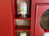 a red cabinet with a mirror and a bottle of liquor