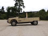 a tan jeep parked in a parking lot with trees in the background
