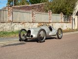 a silver race car that is parked on the side of the road