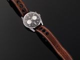 a watch with a brown leather strap sitting on top of a black surface