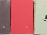 three books sitting next to each other on a white surface
