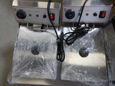 two electric fryers sitting on top of a counter covered in plastic