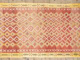 a red and yellow rug on a wooden floor