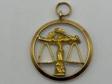 a gold plated pendant with an image of a woman holding a scale