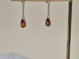a pair of earrings hanging from a stand on a table