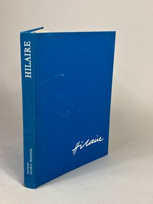 un livre bleu posé sur une table à côté d'un mur blanc