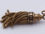 a picture of a gold tassel on a white surface