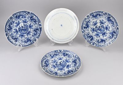 trois assiettes bleues et blanches et un bol posé sur un support