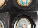 four miniature portraits of women in formal dress are displayed in a black frame