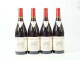 quatre bouteilles de vin rouge sont alignées sur une surface blanche