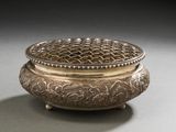 an ornate silver box with a lid on a gray surface