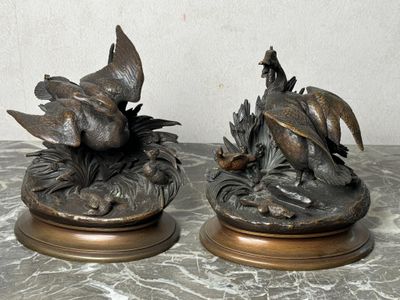 deux statues d'oiseaux en bronze posées sur une table en marbre