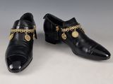 une paire de chaussures en cuir noir ornées de chaînes dorées
