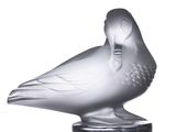 une sculpture en verre représentant un oiseau posé sur un socle