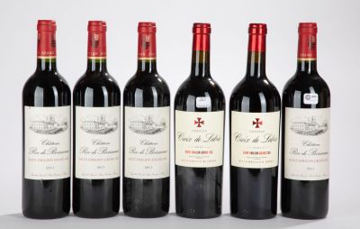 six bouteilles de vin rouge alignées sur une surface blanche