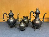 trois théières en argent et une cafetière posées sur une table