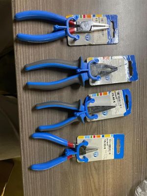 quatre pinces bleues posées sur une table en bois, à côté d'une paire de ciseaux
