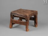 an old wooden stool sitting on top of a gray surface
