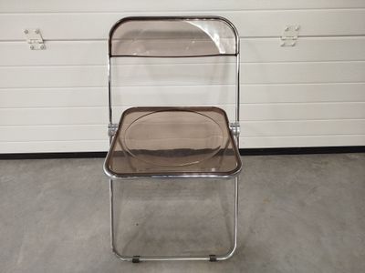 une chaise en plastique transparent avec une assise marron, placée devant une porte de garage